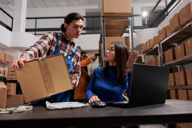 warehouse carrier operator managing parcel shipping handling asian man woman colleagues discussing goods logistics supply chain schedule laptop storage room 482257 60891
